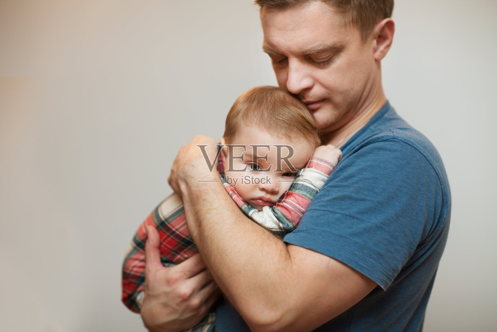 父亲握着伤心的小婴儿的手。家庭的概念。在婴儿的牙齿被剪。照片摄影图片