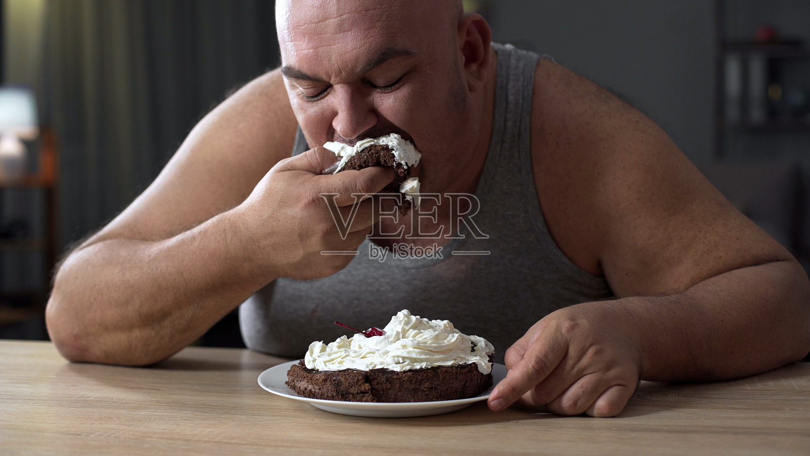 邋遢的胖子贪婪地吃着奶油蛋糕，嗜吃甜食照片摄影图片