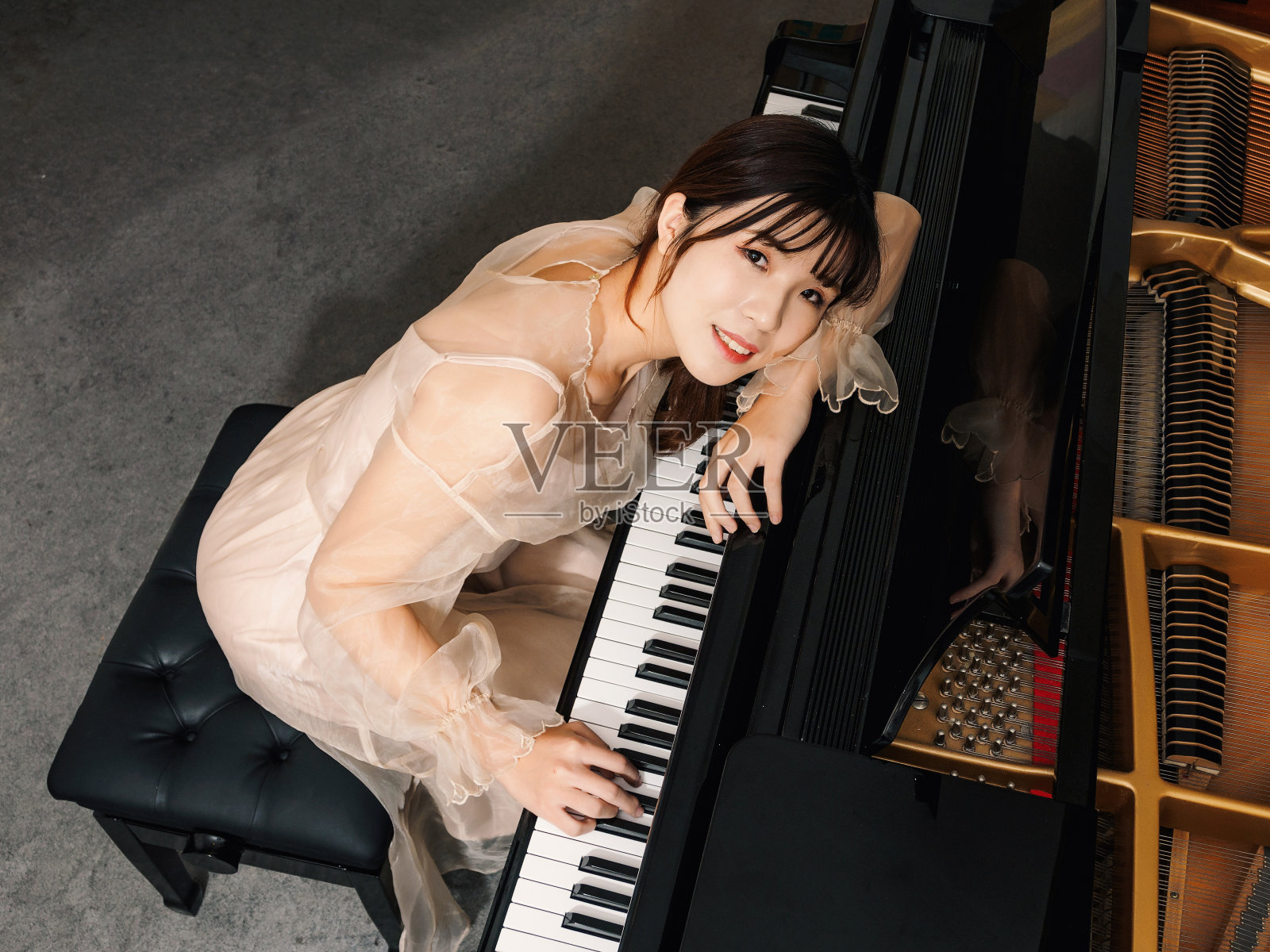 中国女孩和大钢琴。漂亮的年轻女孩钢琴家。照片摄影图片