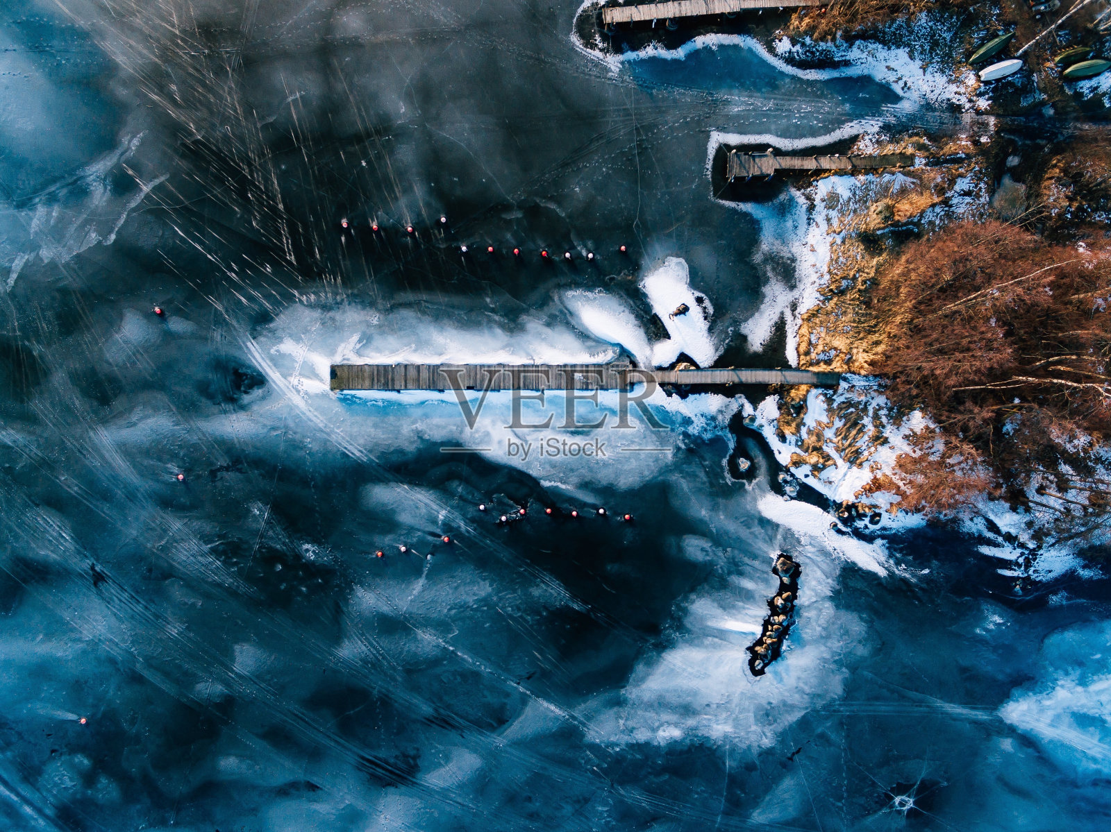 芬兰无人机拍摄的冬季冰冻湖的鸟瞰图，上面有木栈桥。照片摄影图片