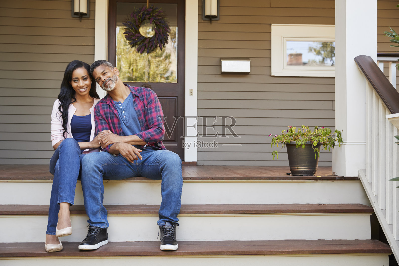一对夫妇坐在台阶上通向家的门廊照片摄影图片