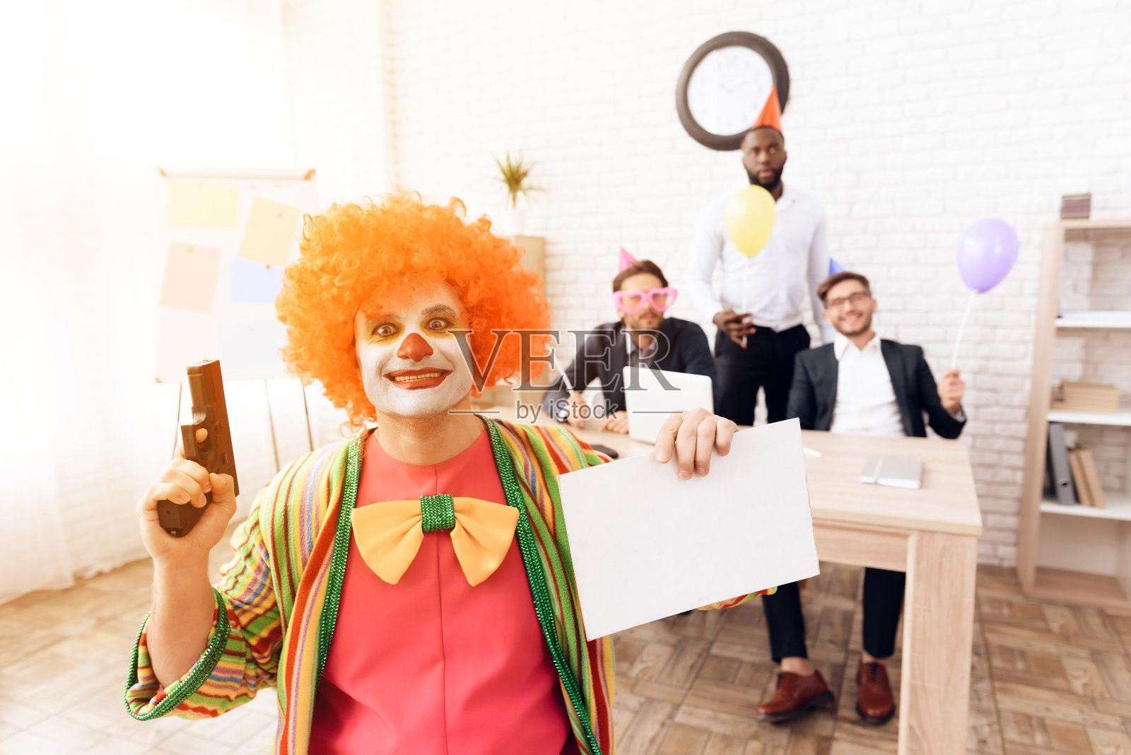 4月1日，一名身穿小丑服、头戴假发的男子坐在商务办公室里。照片摄影图片