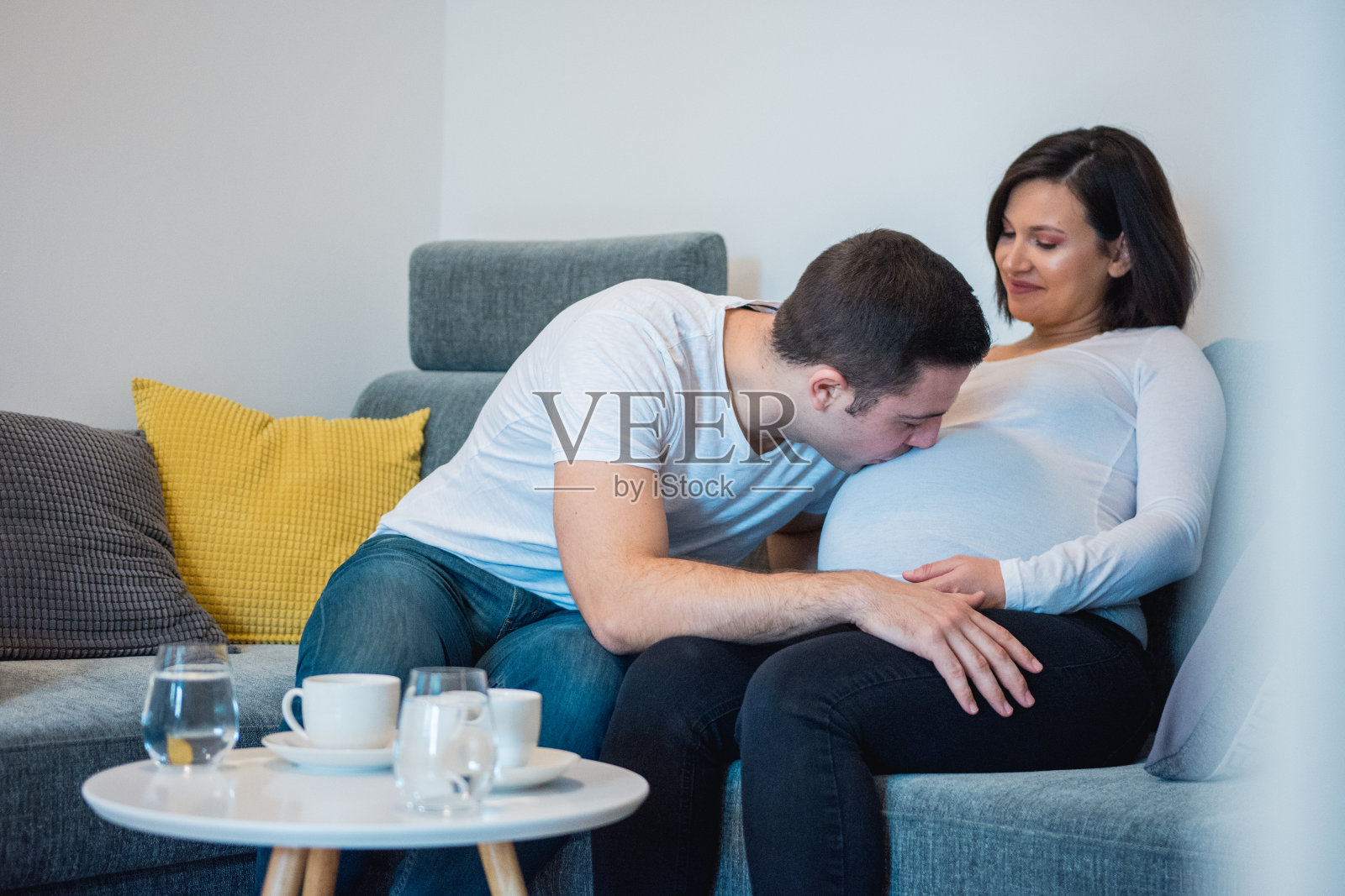 男人亲吻他怀孕的妻子的肚子照片摄影图片