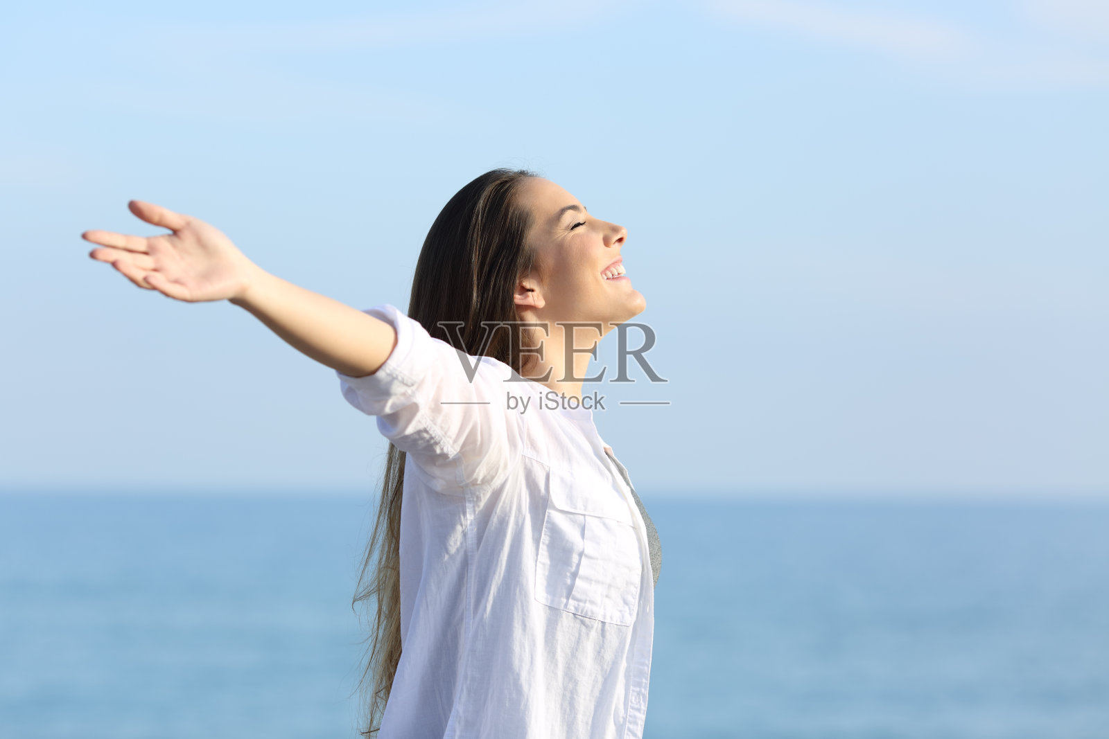 女孩在海滩上伸展双臂呼吸新鲜空气照片摄影图片