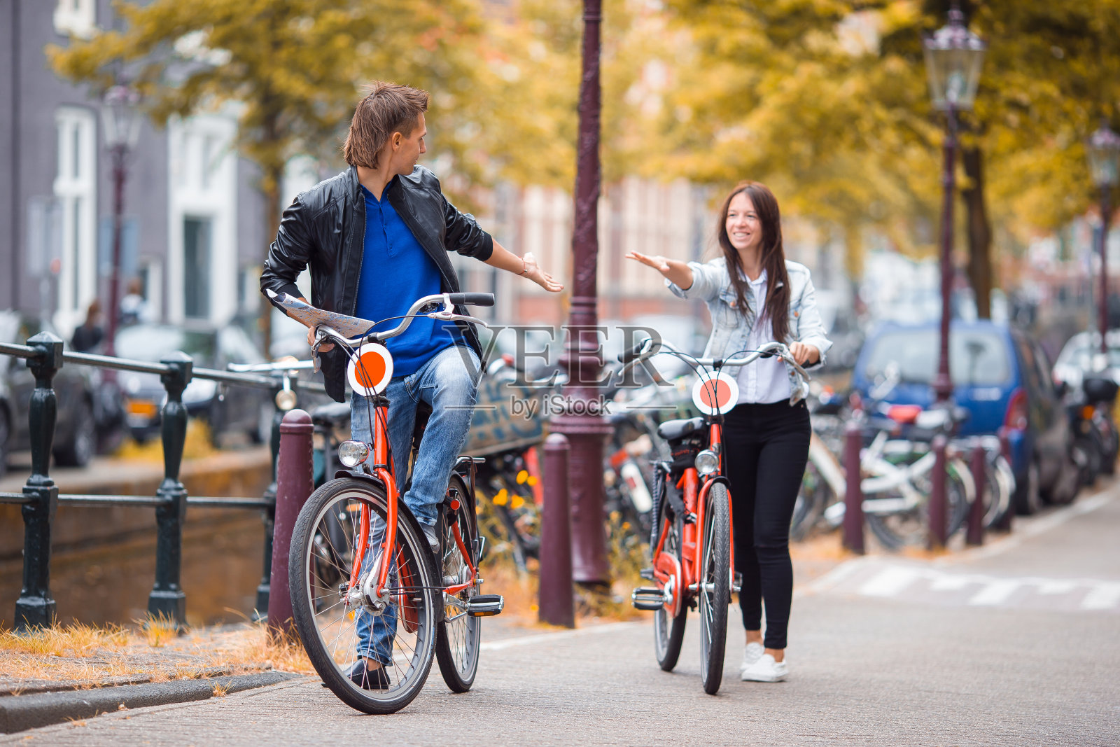 年轻幸福的白人夫妇在阿姆斯特丹的老街上骑自行车照片摄影图片