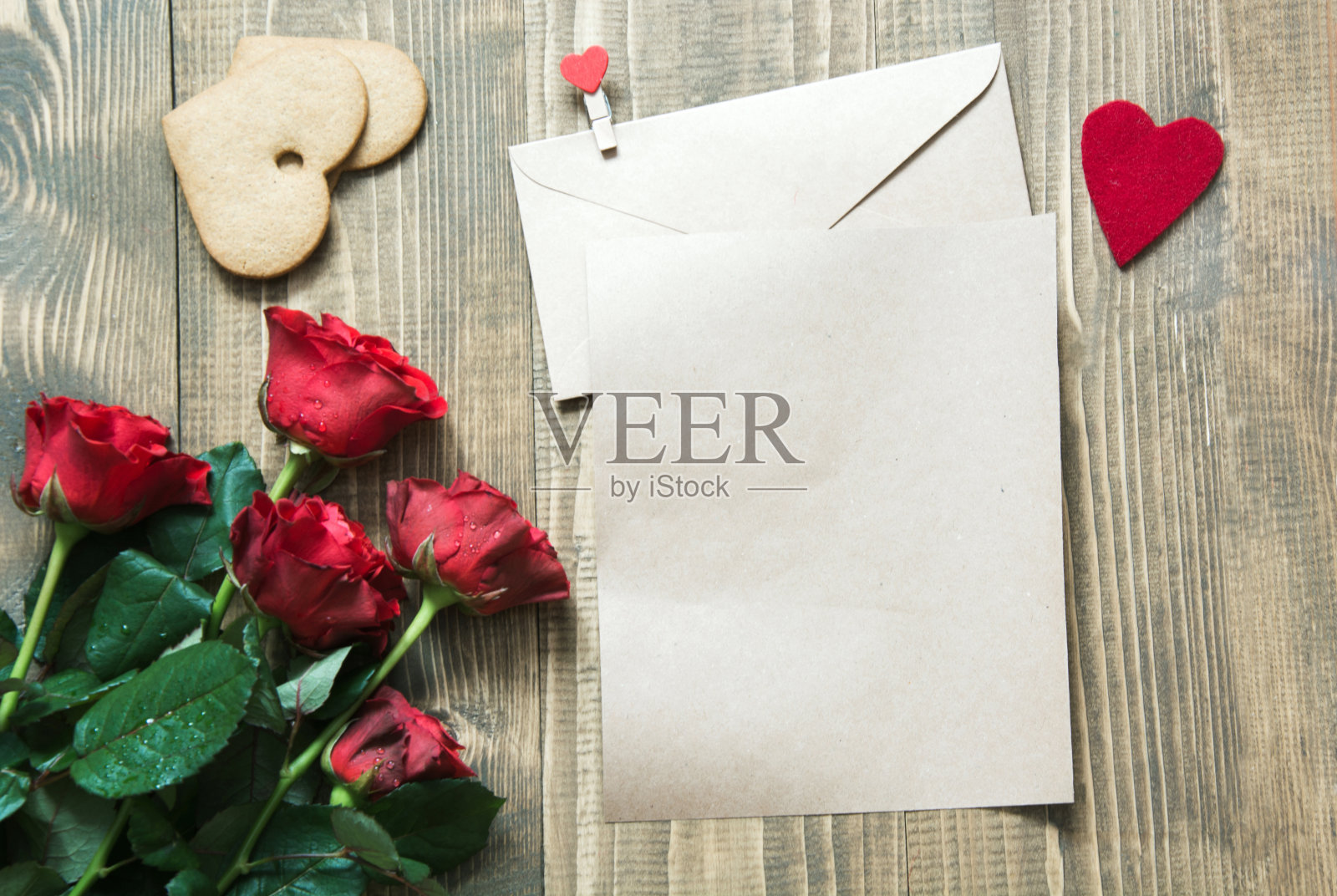情人节贺卡与花束红玫瑰花，心作为空白和礼物盒放在木桌上。副本的空间。照片摄影图片