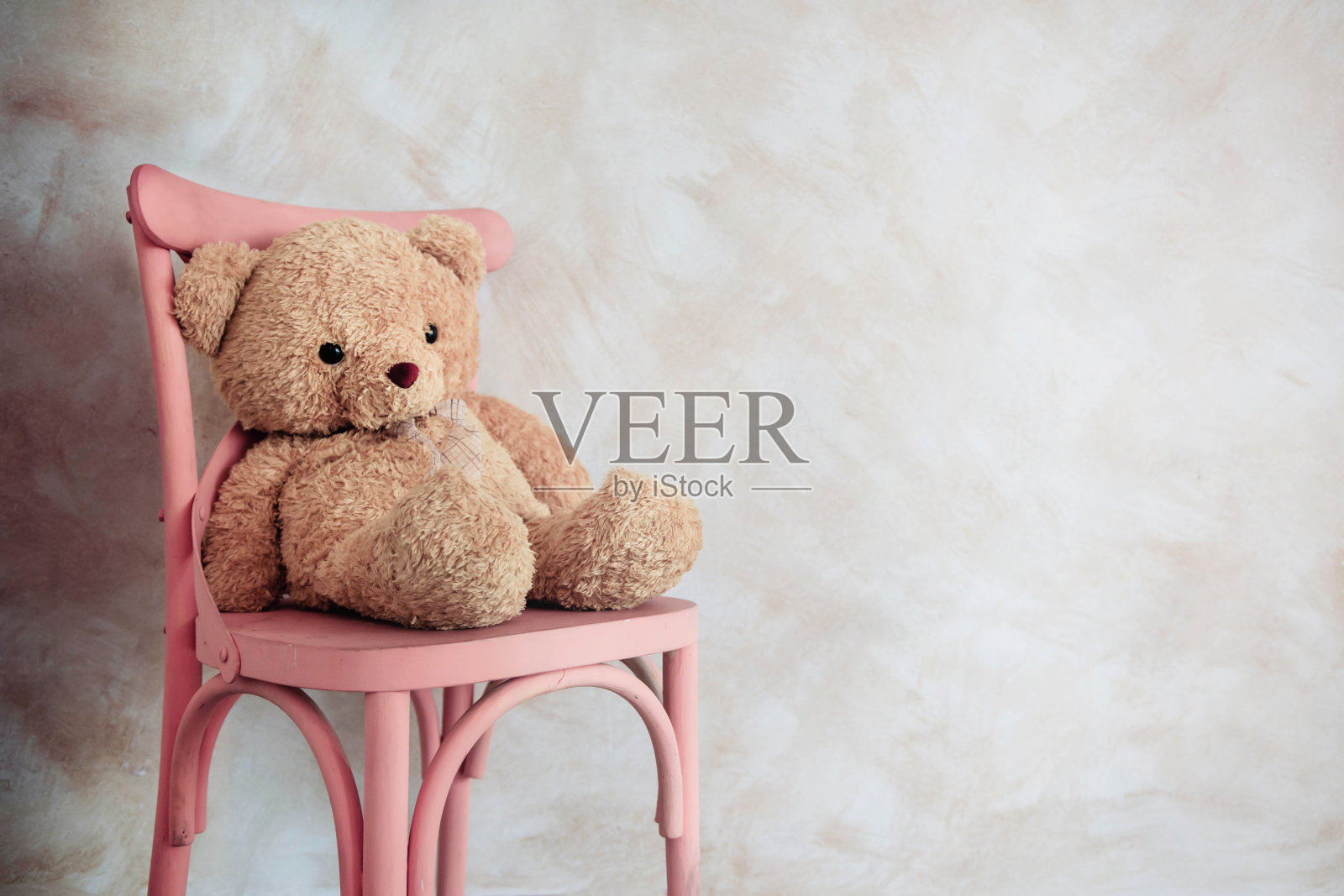 悲伤和孤独的概念。孤独的泰迪熊独自坐在屋里的椅子上照片摄影图片