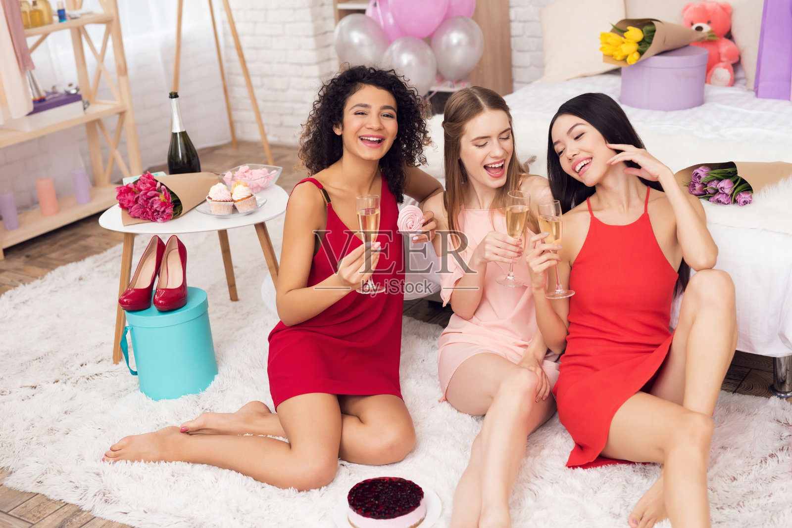 三个女孩拿着糖果和香槟。他们正在庆祝3月8日的妇女节。照片摄影图片