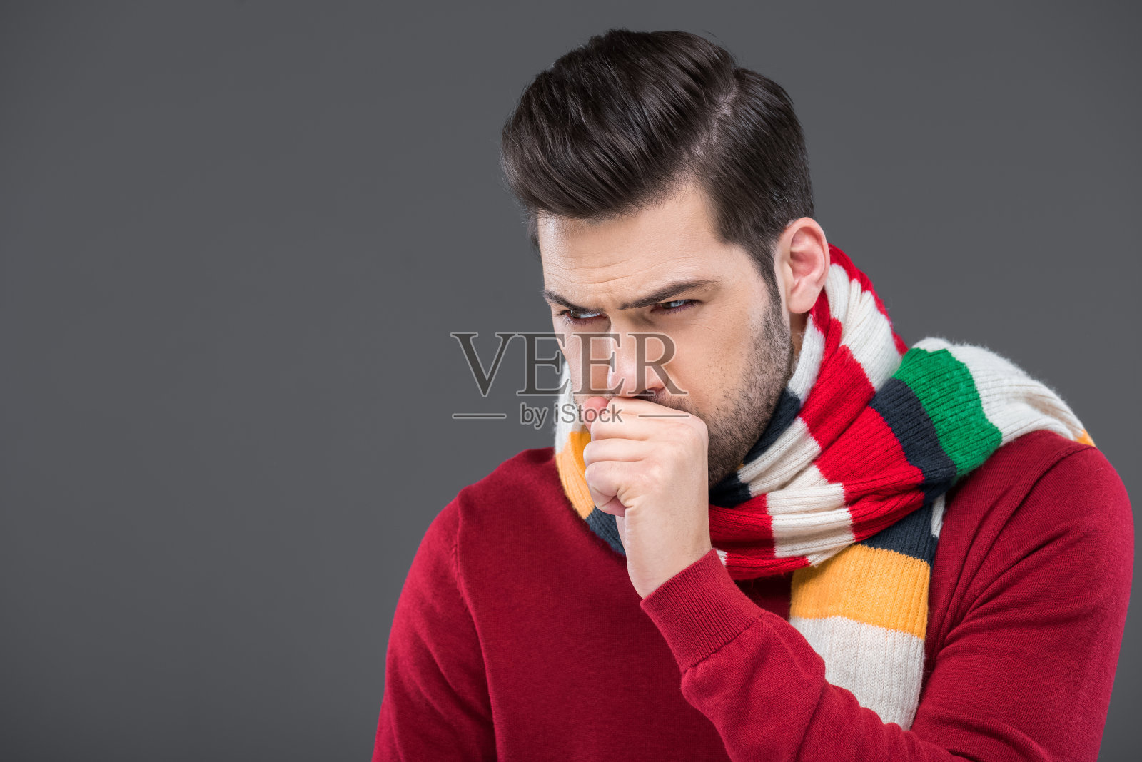 病人在温暖的围巾中咳嗽，孤立在灰色照片摄影图片