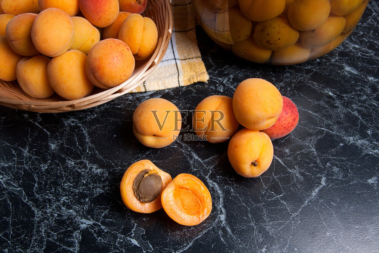 收获的杏在篮子和罐子与杏罐头蜜饯照片摄影图片
