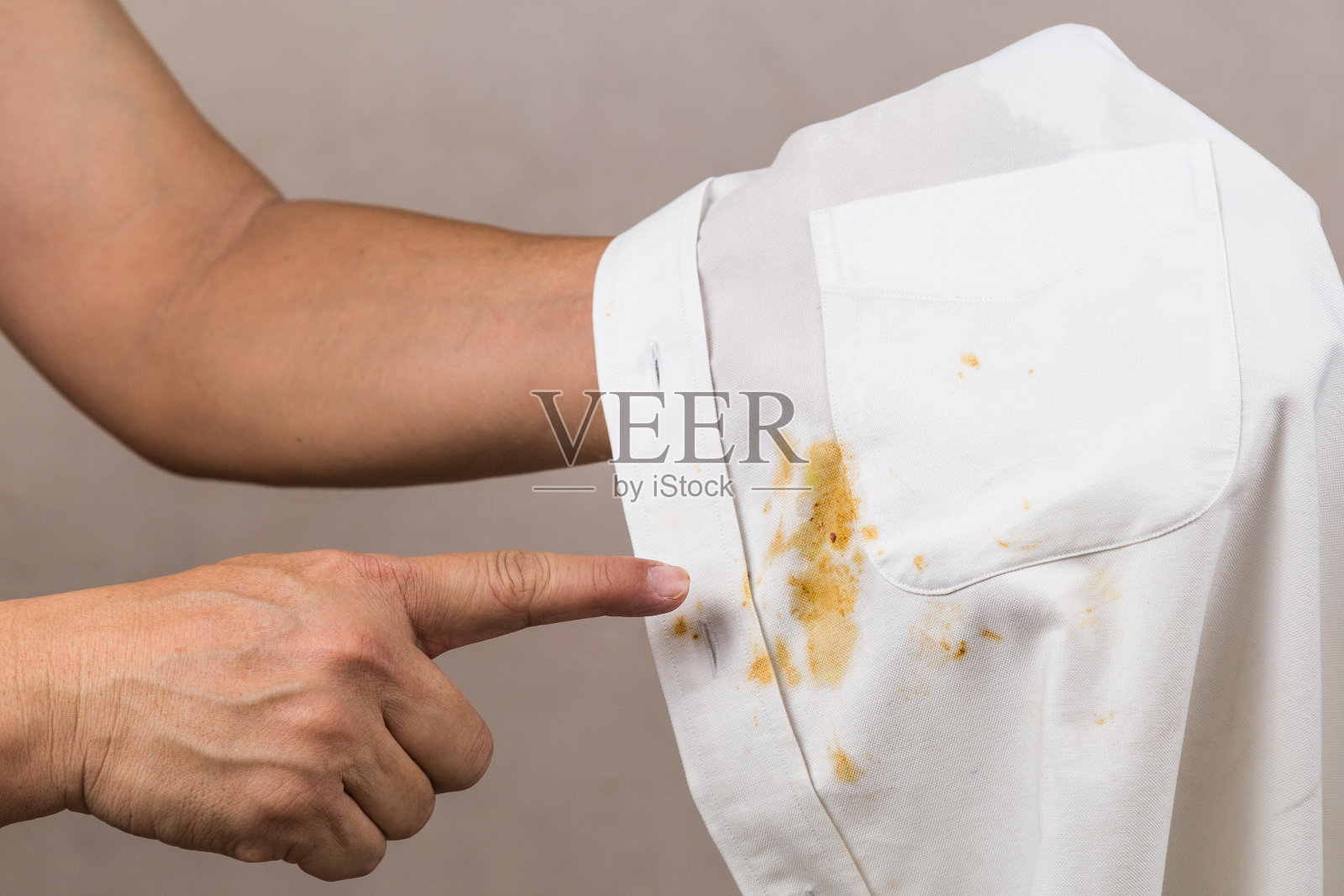 有人指着洒在白衬衫上的咖喱污渍。照片摄影图片