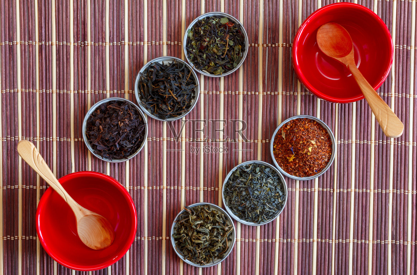 伊万茶，马拉喀什rooibos，红茶，绿茶和木汤匙在红碗上的棕色竹垫，俯视图特写照片摄影图片