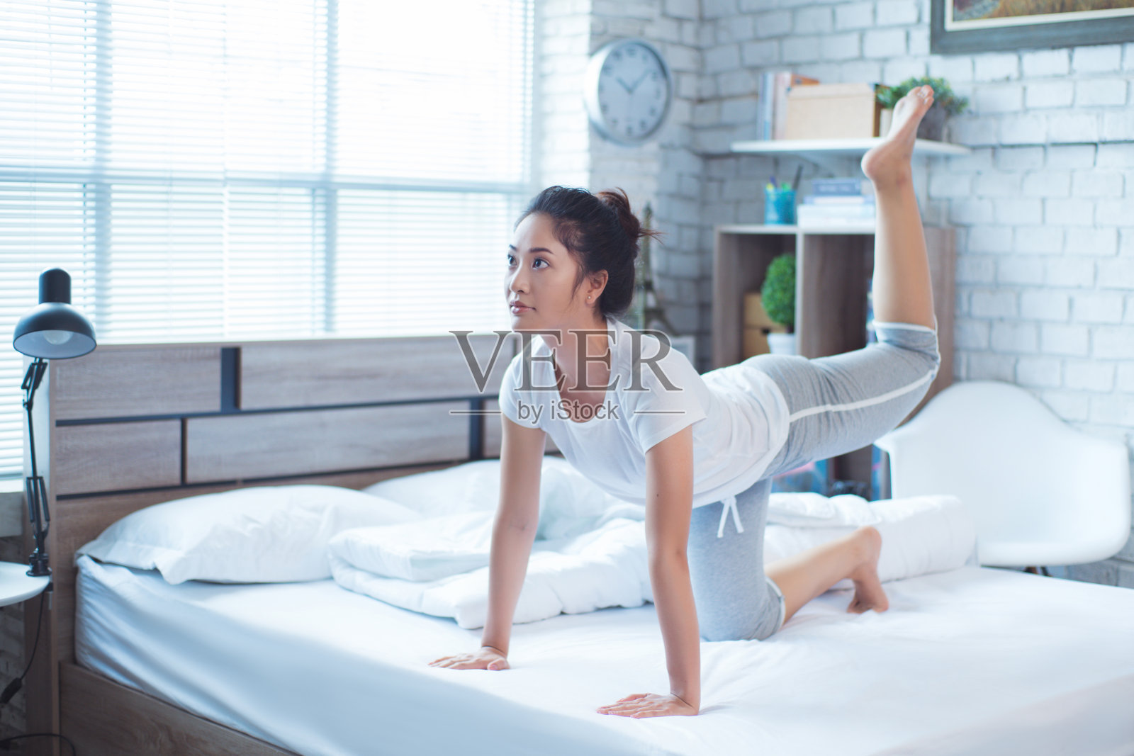 亚洲女性早上在床上锻炼，她觉得精神焕发。照片摄影图片