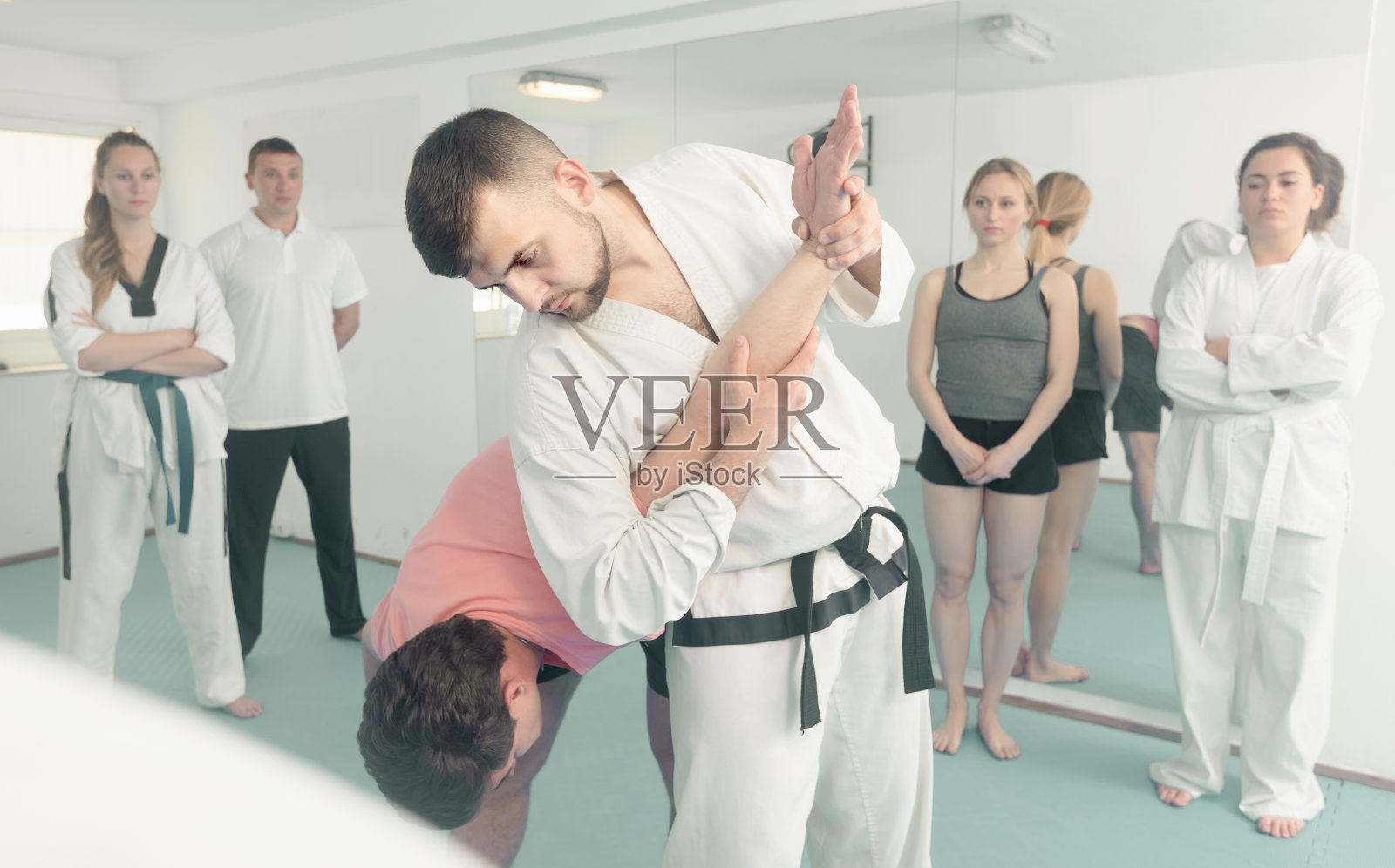 男子训练新的跆拳道与成人在课堂上举行照片摄影图片