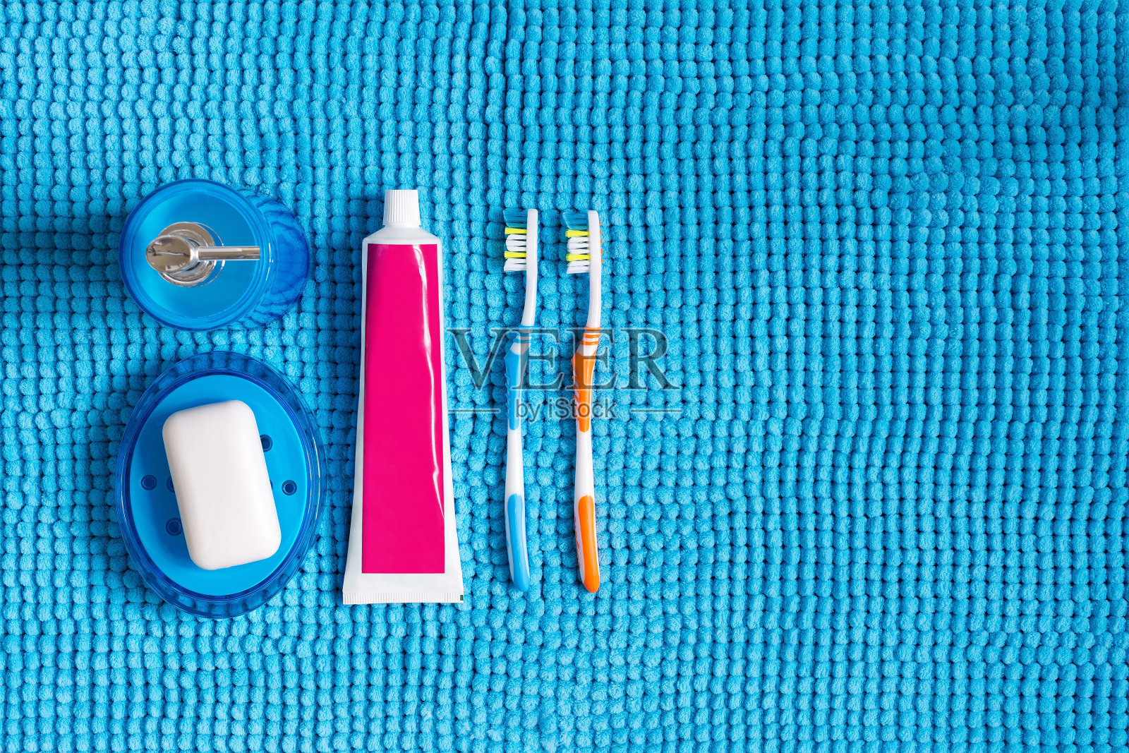 彩色牙刷，牙膏管，蓝色液体洗涤剂分配器和带有白色肥皂的肥皂盘。照片摄影图片