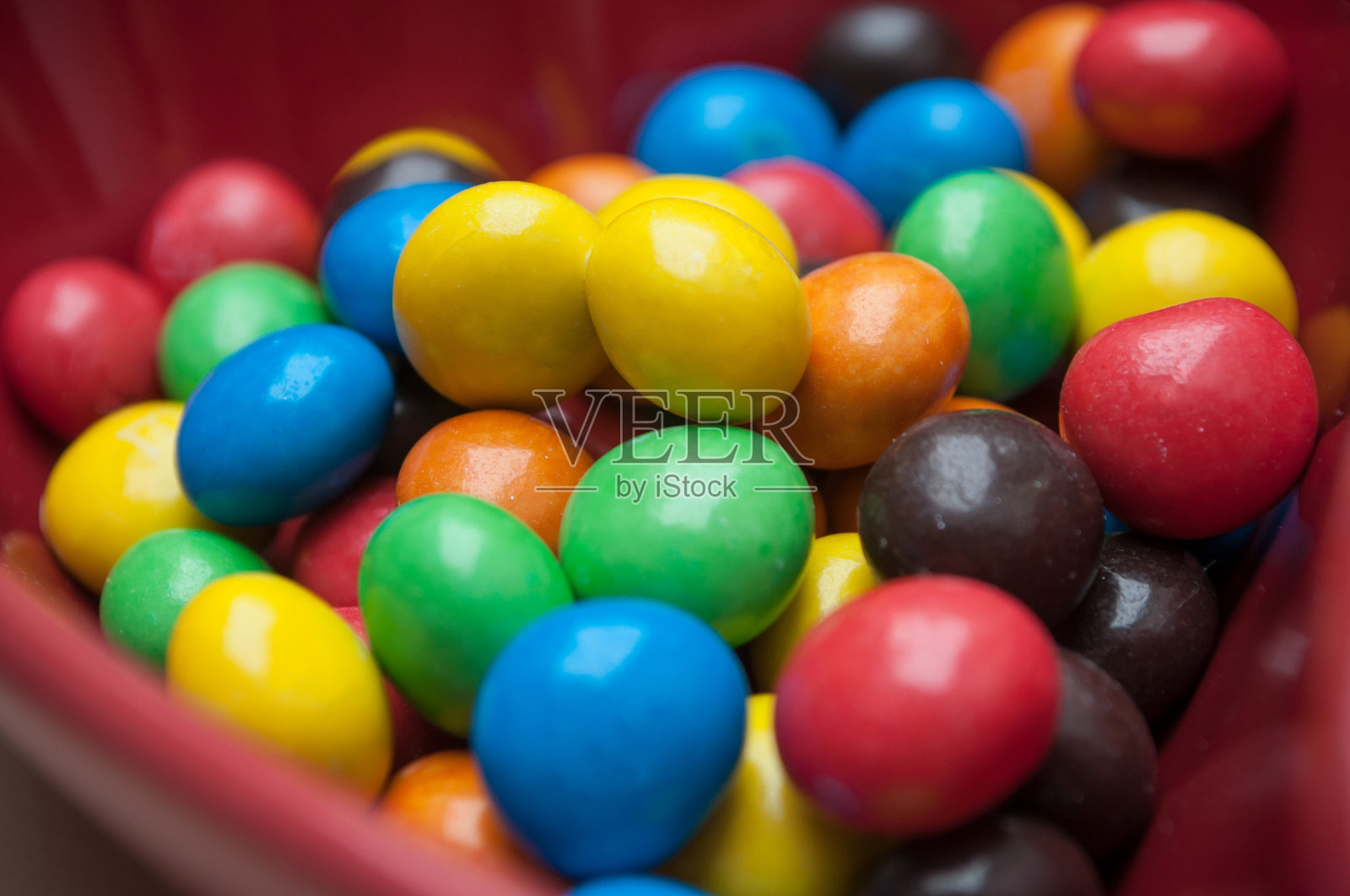 五彩缤纷的巧克力糖果放在一个红色的心形碗里照片摄影图片
