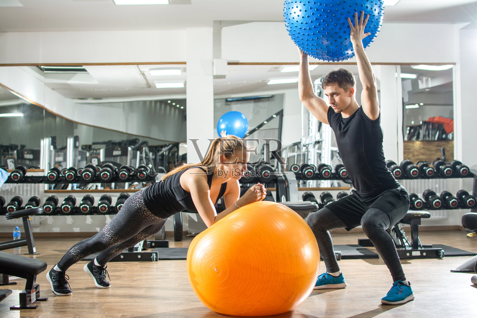 年轻的女人和男人在健身房用健身球锻炼。照片摄影图片