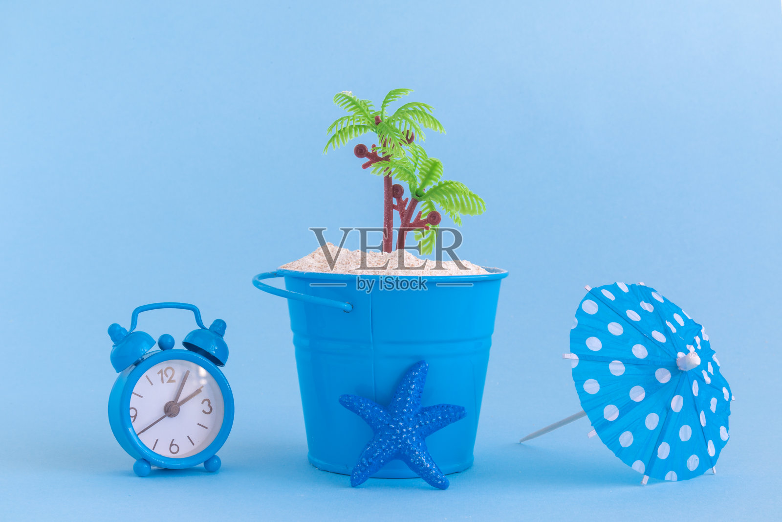 海星，纸伞，可以与沙子和塑料棕榈树隔离在蓝色的背景。夏季假期极简主义的静物生活概念。照片摄影图片