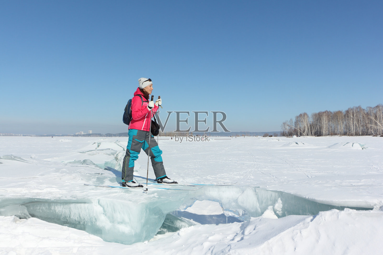 快乐的女人滑雪者在红色夹克站在一个冻结的河上，鄂毕水库，俄罗斯照片摄影图片