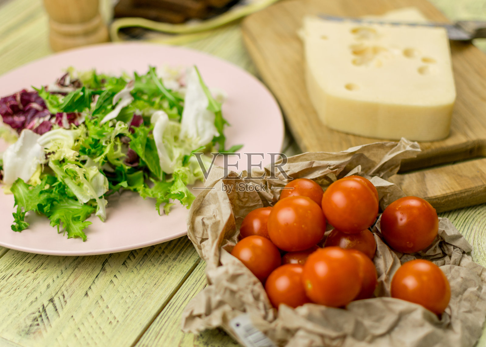 一块奶酪和新鲜蔬菜旁边的一个木制表面。照片摄影图片