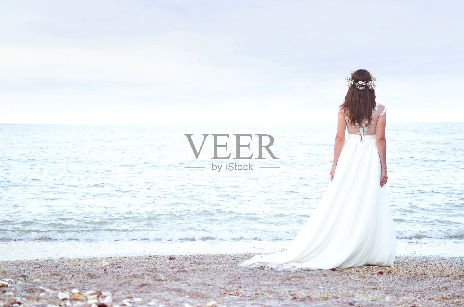美丽的新娘站在海面上。新娘在海滩上散步照片摄影图片