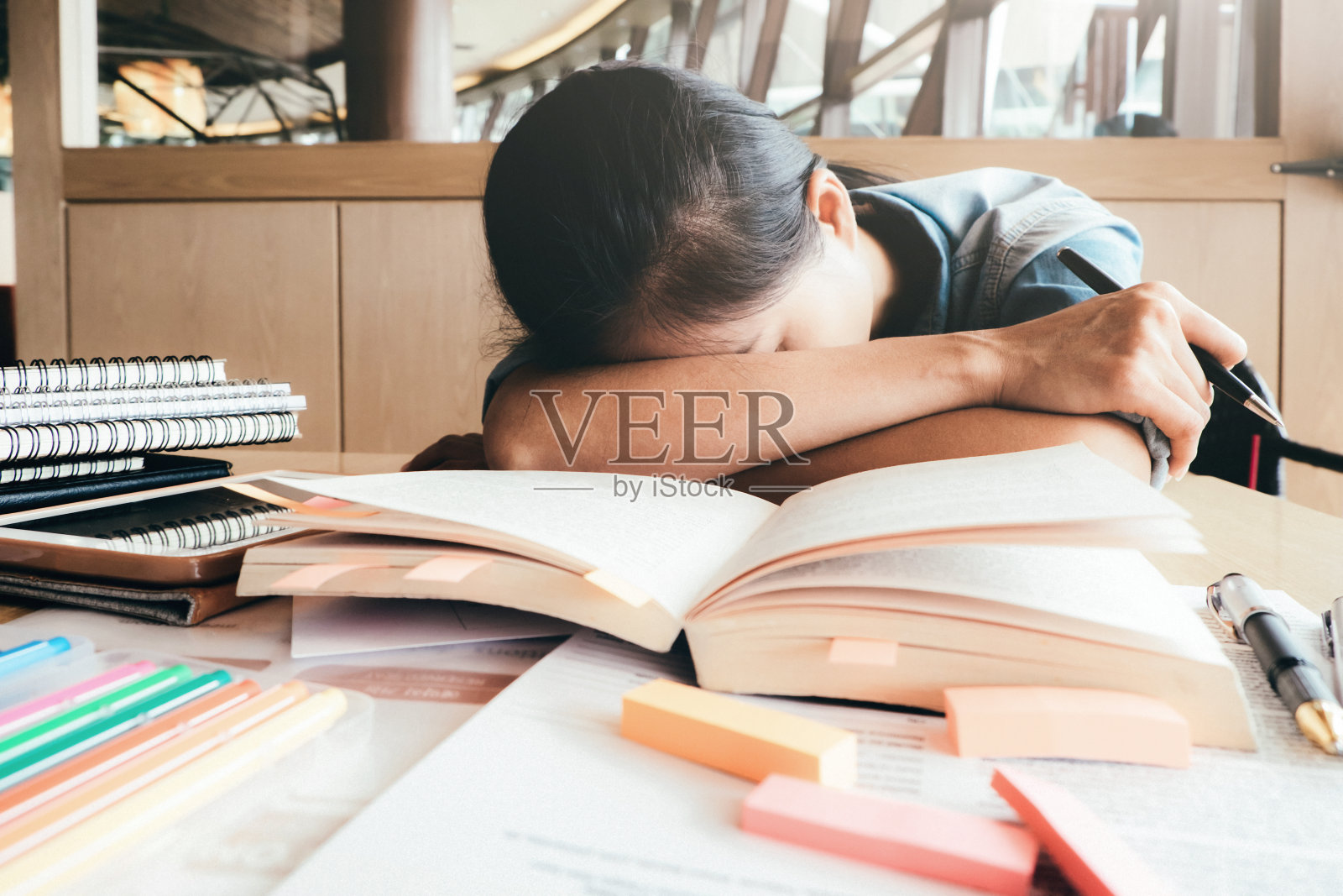 女孩苦读，睡在图书馆里。照片摄影图片