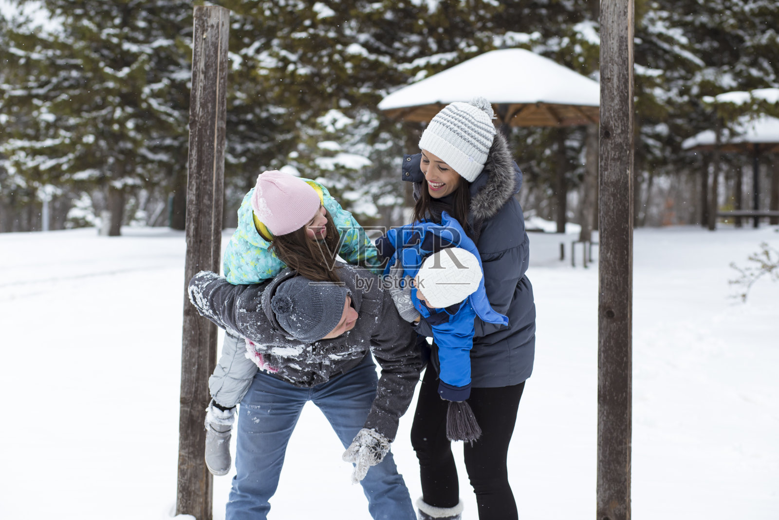 爸爸和妈妈带着他们的孩子，在雪里玩。照片摄影图片