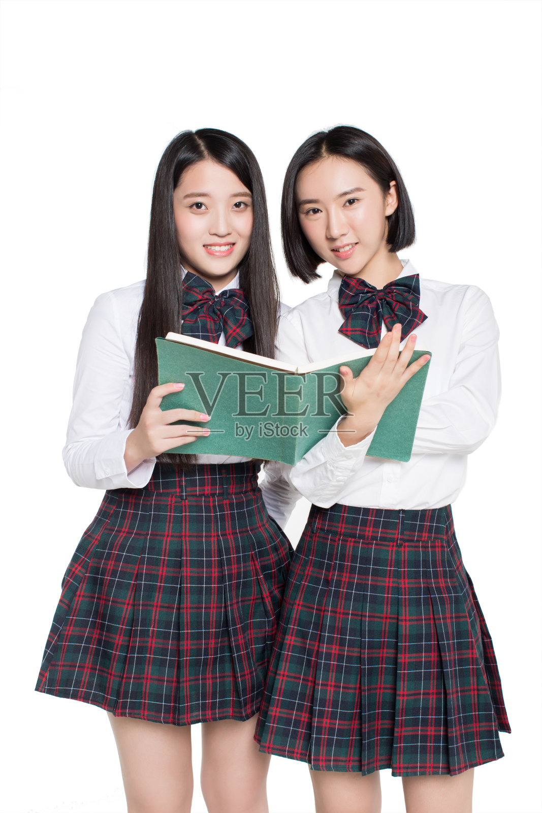 两个快乐的十几岁的女孩在读一本白色背景的书照片摄影图片