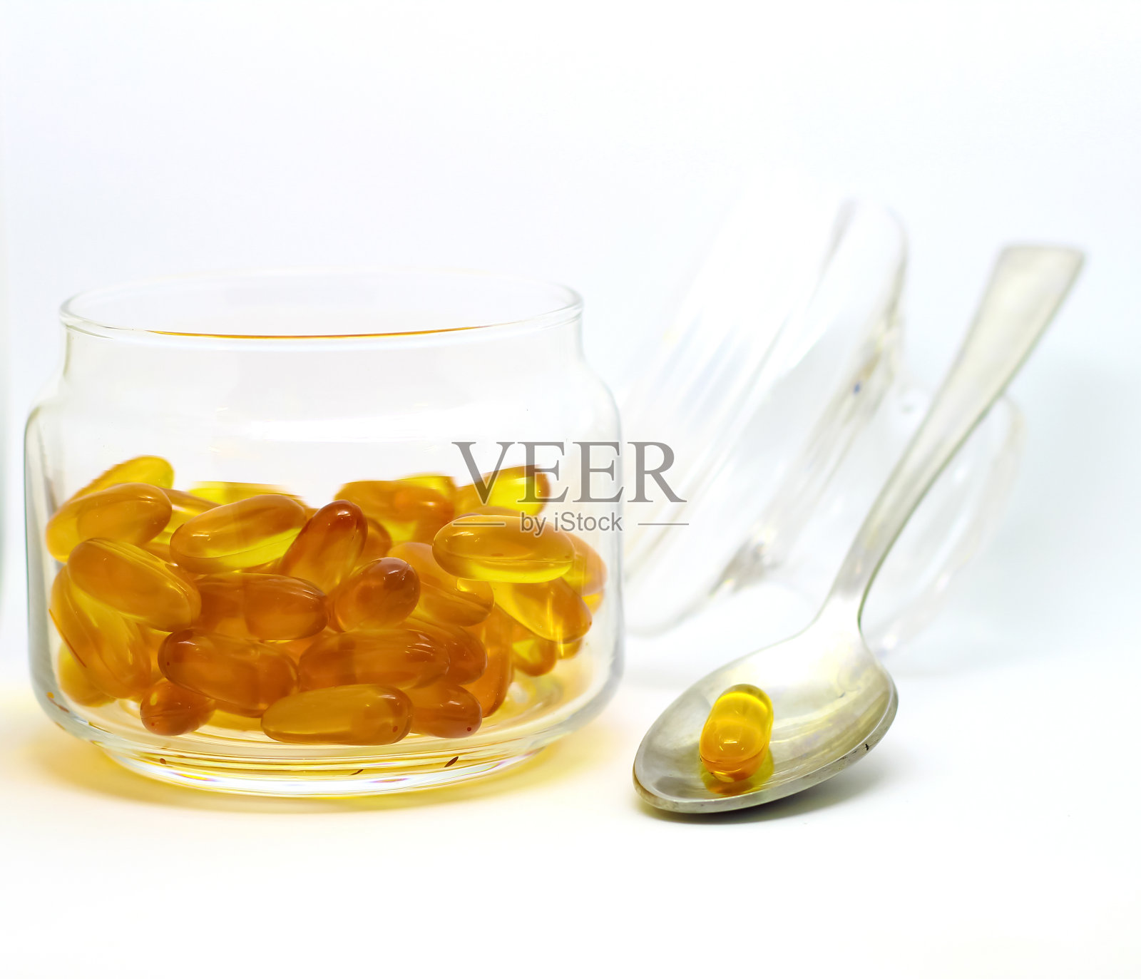 鱼肝油- 3维生素e凝胶胶囊孤立在白色背景的透明玻璃瓶与钢匙照片摄影图片