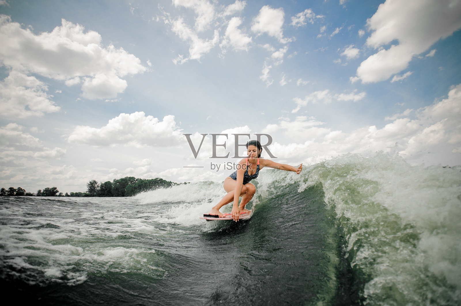 女人骑着尾流板在高浪吐出水花照片摄影图片