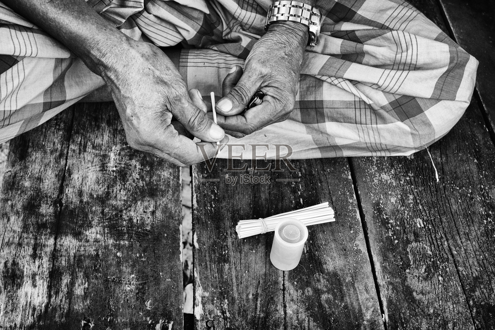 老人手握自制的干烟草和尼帕叶香烟。照片摄影图片