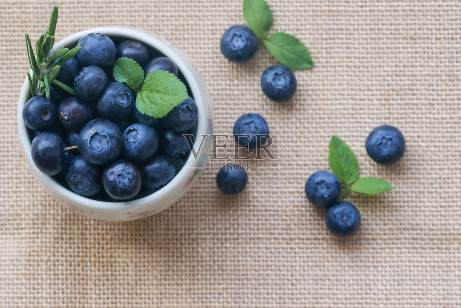 新鲜成熟的野生蓝莓在白色碗上的乡村袋在俯视图平躺与副本空间为背景。蓝莓是抗氧化食品和维生素c，是健康美味的水果概念。照片摄影图片