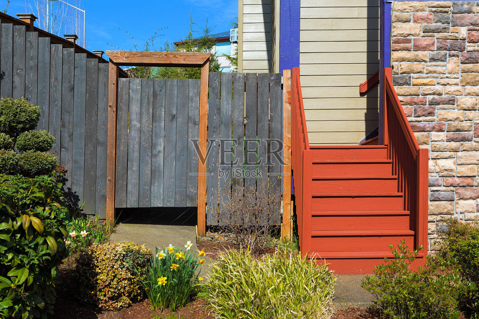 家花园前院与植物，木栅栏门，彩色楼梯的侧面和石墙照片摄影图片