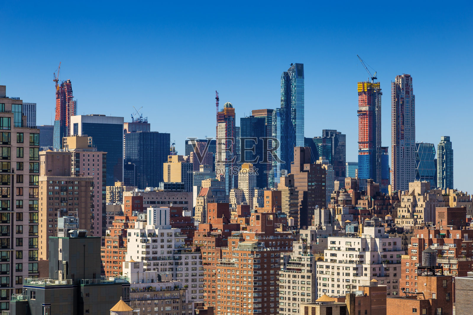 纽约市的天际线，有正在建设的小足迹的高楼大厦，上东区和中城的豪华高层公寓和生动的蓝天。照片摄影图片