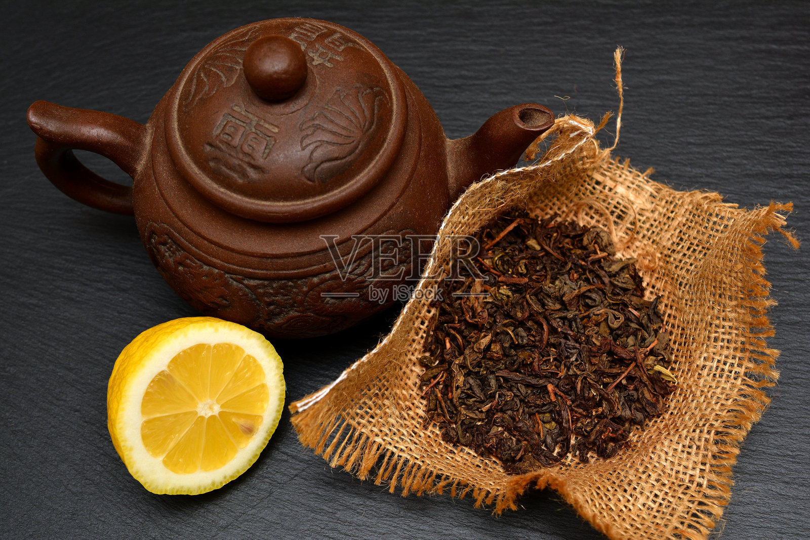 茶壶，半熟柠檬，干茶叶在黑板，盘子或托盘。照片摄影图片
