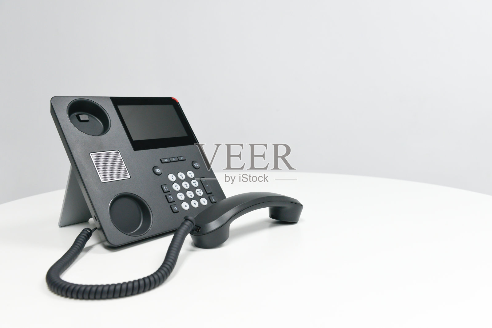 黑色IP话机，会议室白色桌上放置办公话机照片摄影图片