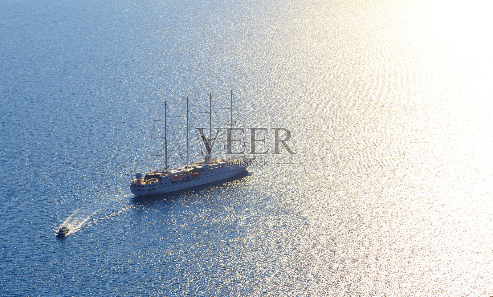 俯视着希腊圣托里尼海岸外的一艘带帆和救生船的大木船照片摄影图片