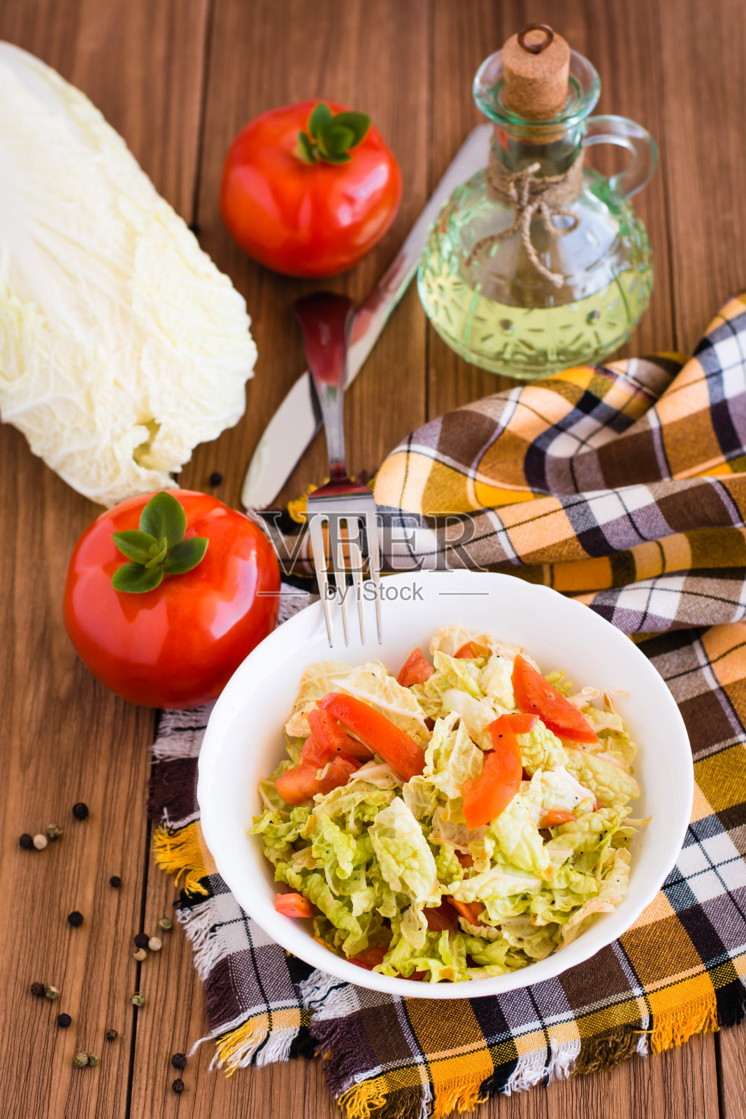 一盘西红柿和白菜做成的即食沙拉，蔬菜和一瓶油照片摄影图片