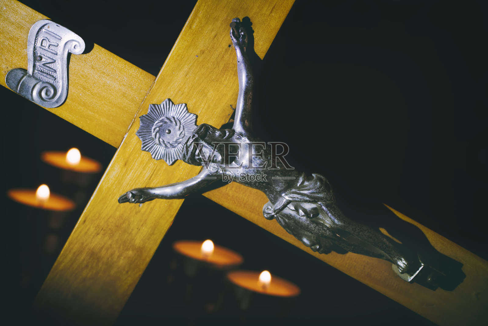 十字架和燃烧的蜡烛在黑暗中。向耶稣基督祷告。照片摄影图片