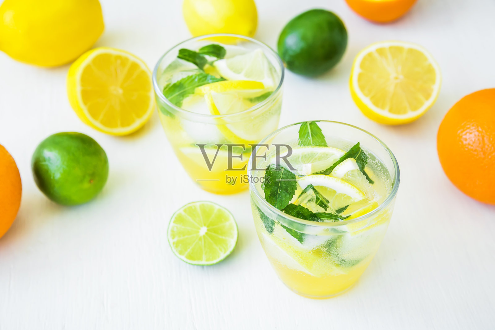 用玻璃杯盛着柠檬、薄荷和柠檬的柠檬汁，放在白色的桌子上照片摄影图片