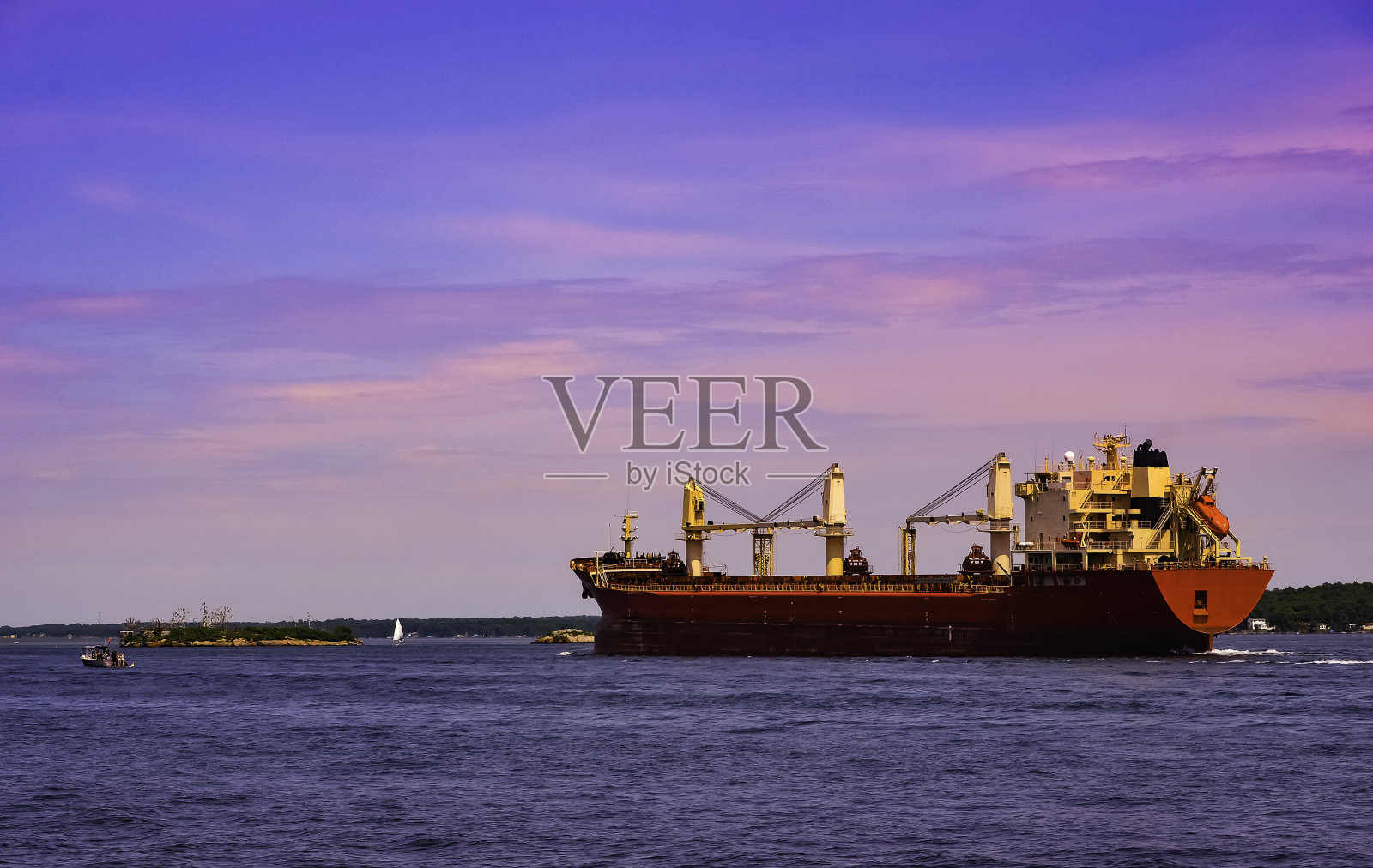 一艘圣劳伦斯河货轮在粉红色的灯光下驶向大海照片摄影图片