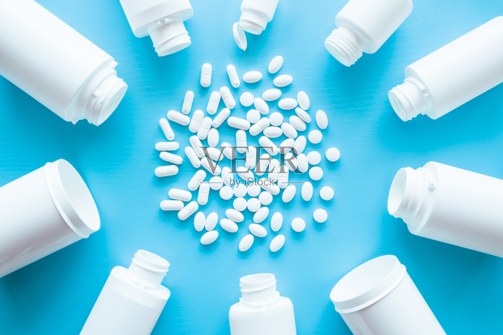 不同的药丸从蓝色背景的白色瓶子里溢出来。模拟特别优惠作为广告或其他想法。医疗、制药和保健理念。照片摄影图片