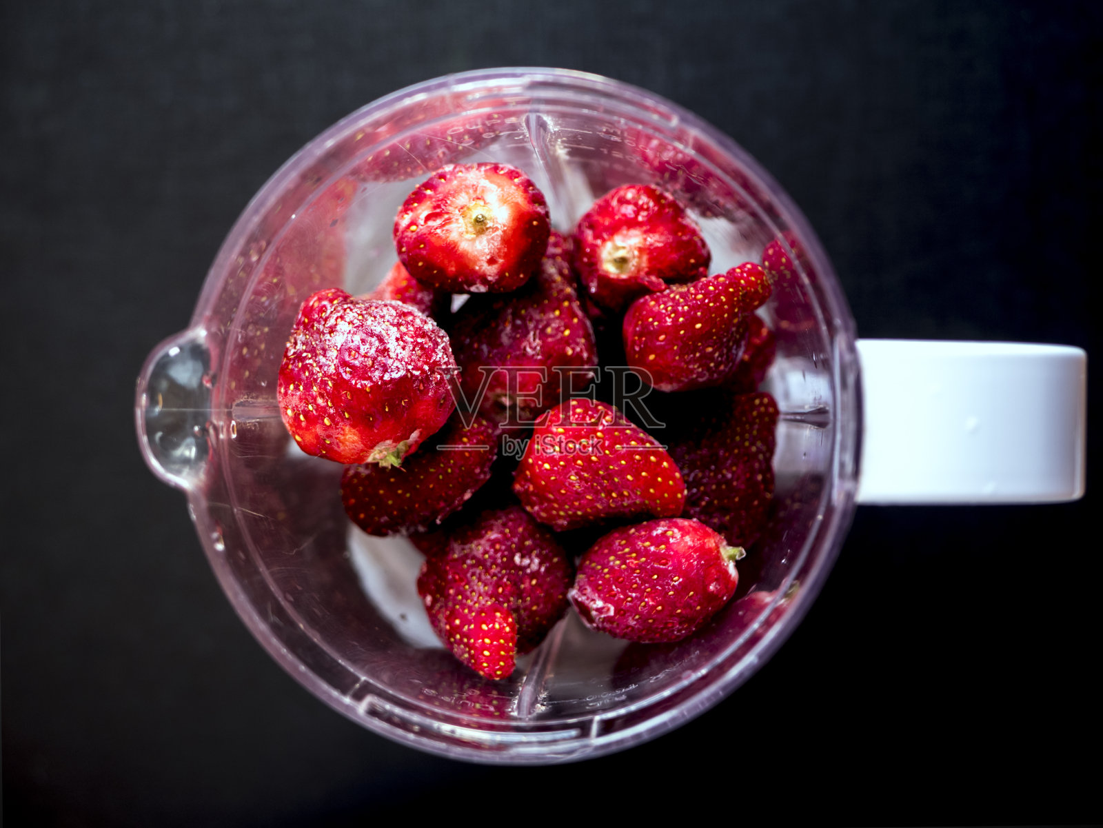 新鲜的冰多汁草莓在搅拌器上从上往下看在黑暗的表面照片摄影图片