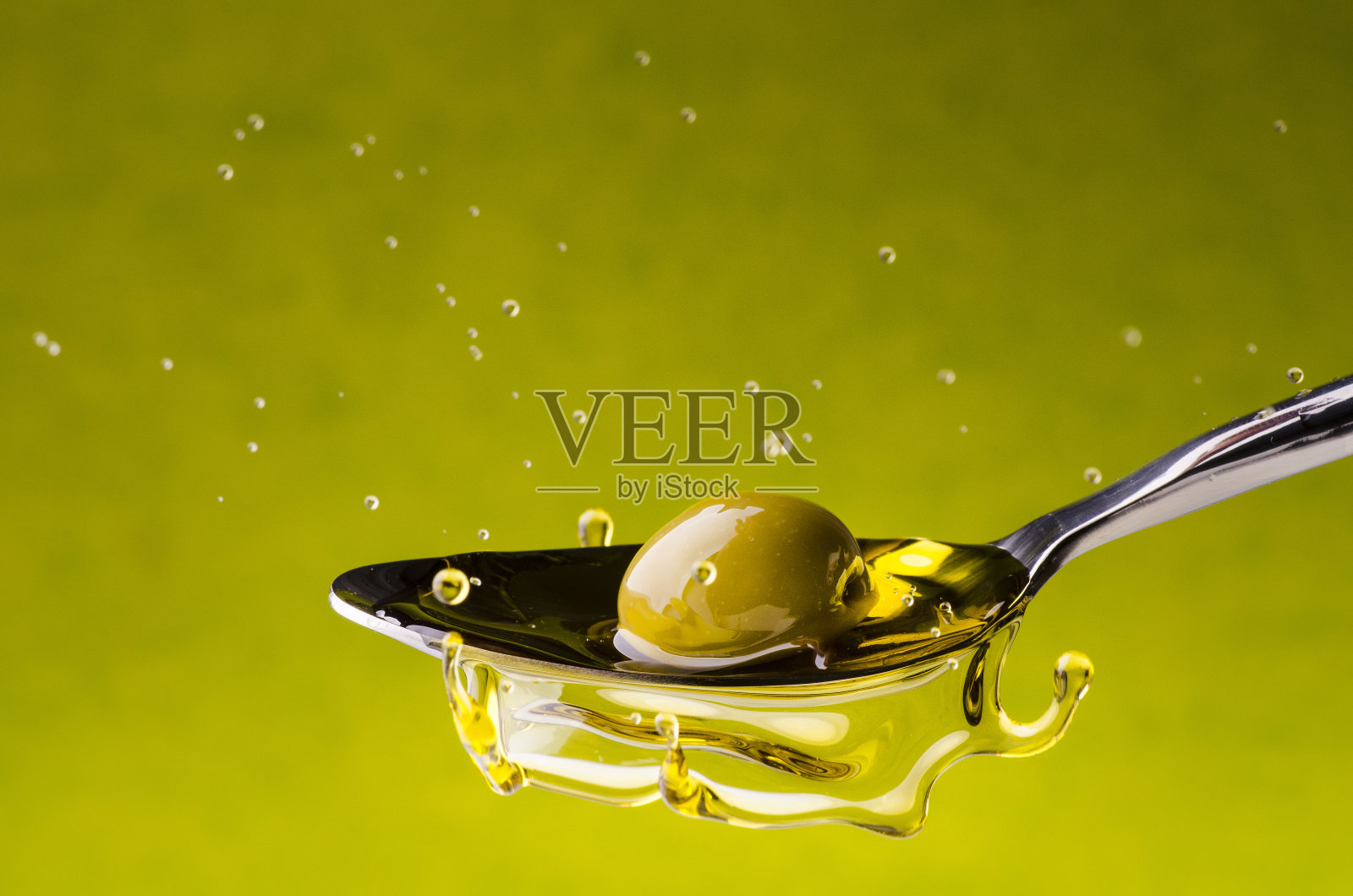 橄榄油和橄榄油一起掉进勺子里照片摄影图片