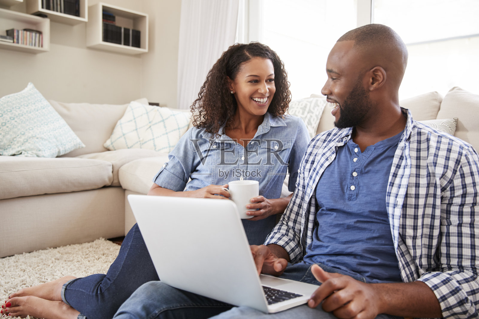 一对年轻的黑人夫妇在家里用笔记本电脑看着对方照片摄影图片
