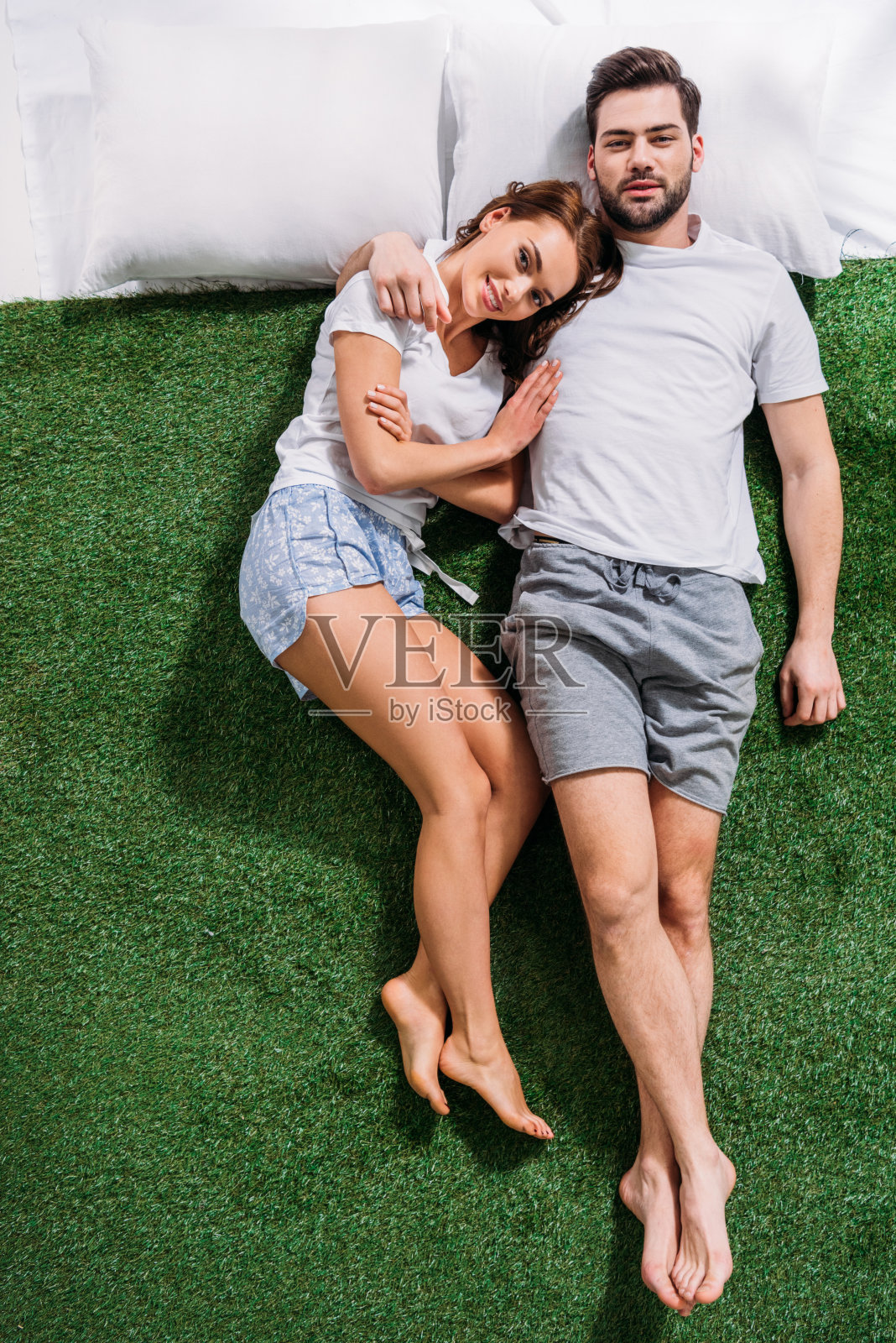 头顶上的年轻夫妇在绿色的草地上躺在枕头上相爱照片摄影图片