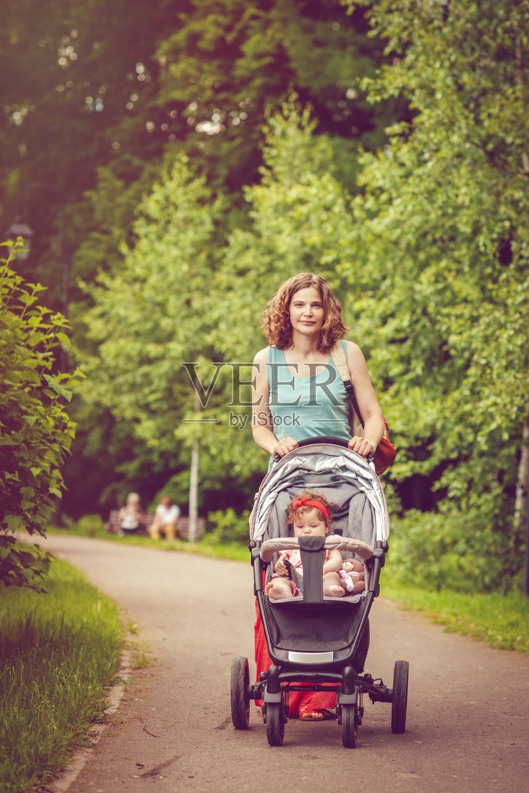 妈妈和她的小女儿在公园里推着婴儿车照片摄影图片