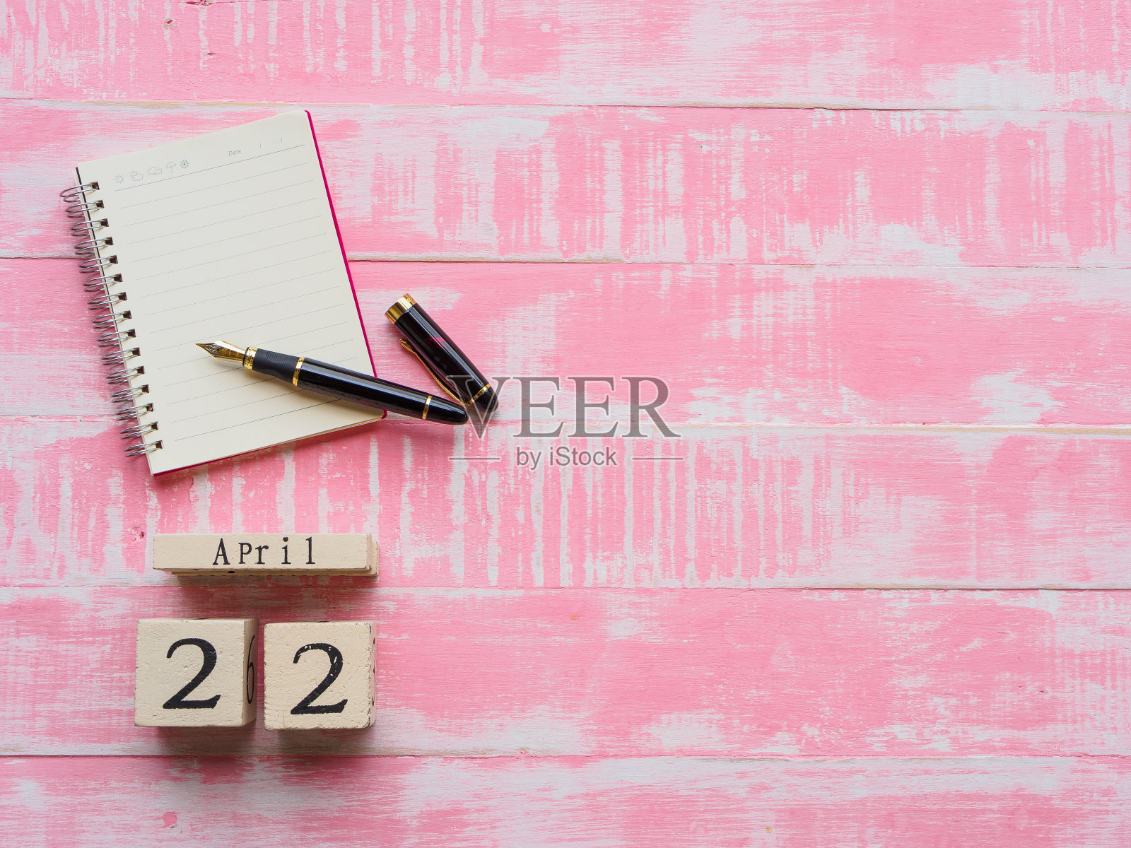 4月22日世界地球日木版日历，木版日历、笔记本和笔都是亮粉色的木质背景纹理。照片摄影图片