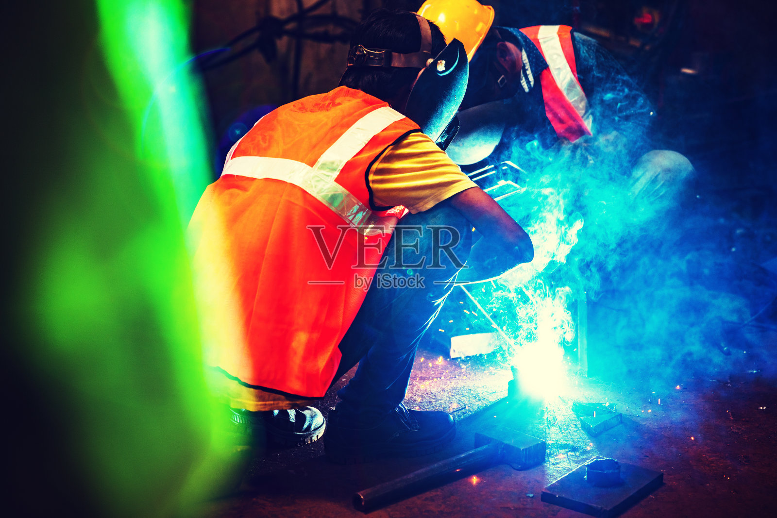 钢铁工业工人蹲在角落里焊接一个零件照片摄影图片