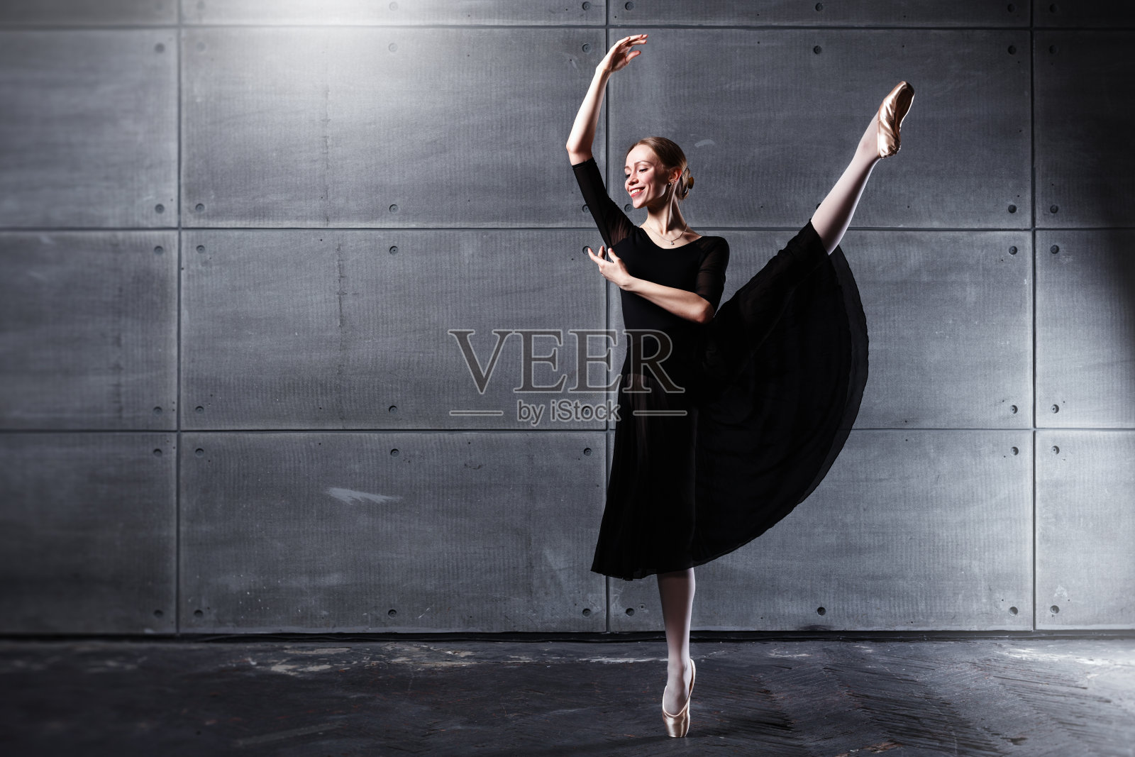 苗条的芭蕾舞女演员在灰色混凝土墙的工作室里摆姿势照片摄影图片